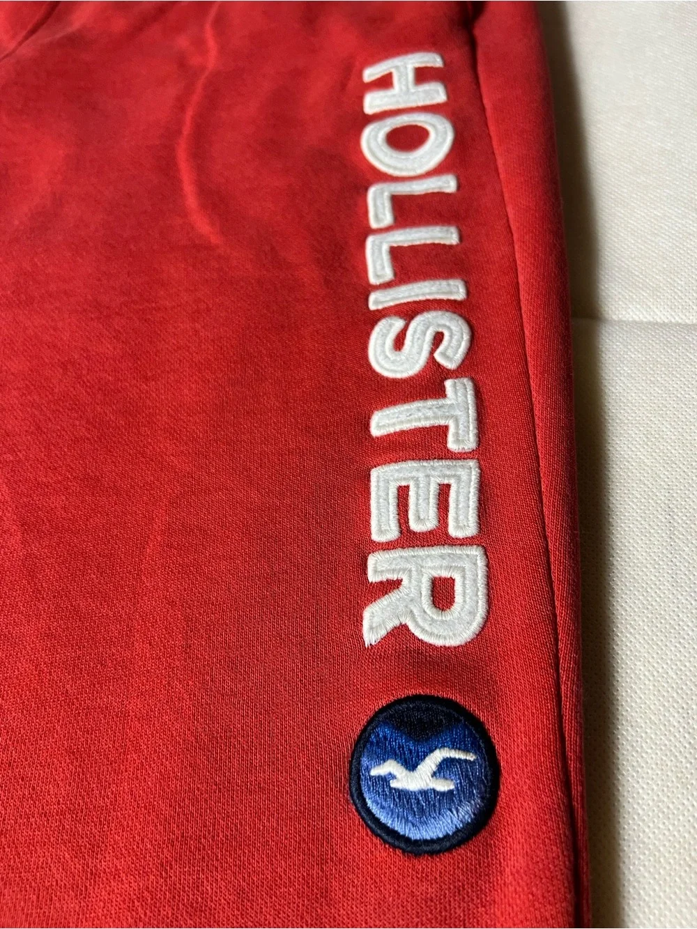 Hollister Co. red sweatpants with white vertical text reading 'HOLLISTER'